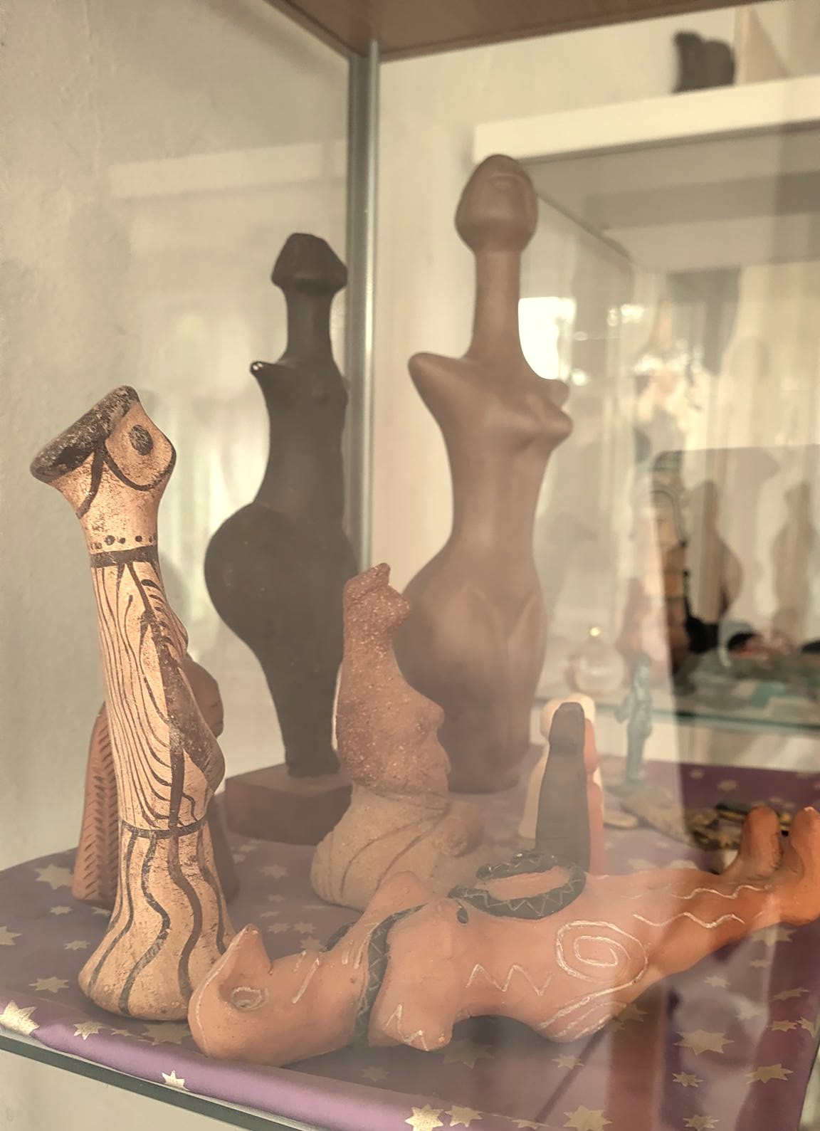 Vitrine mit verschiedenen Göttinen-Statuen aus Keramik und Ton